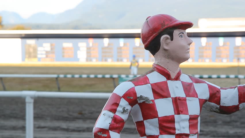 Statue of jockey with horses racing in the background.
