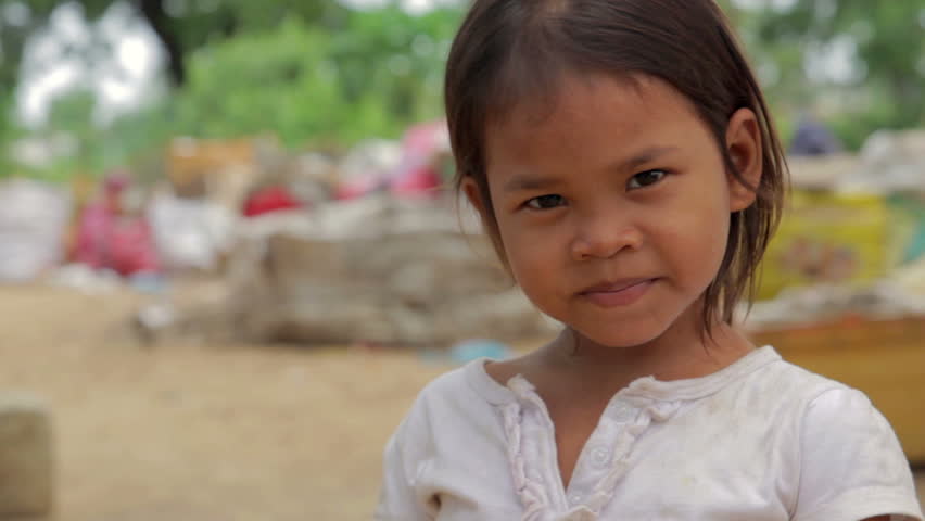Cambodian girl in slums, garbage at background