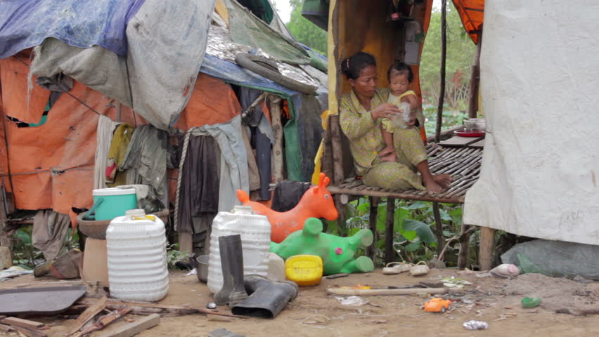 Mother feeding a baby in Cambodian slums, close to dump area