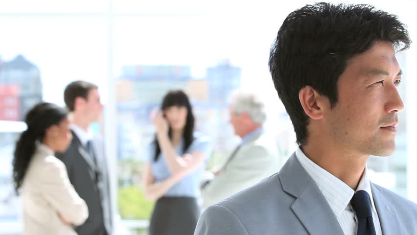 Happy businessman standing upright in front of his team in a bright room