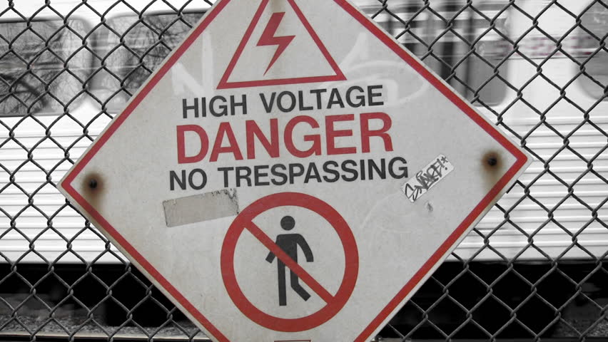 High Voltage DANGER. Subway train speeds past.