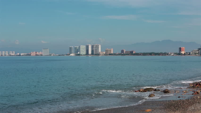 Puerto Vallarta across Banderas Bay beach surf. Boardwalk and Malecon beach and tourist area on shore of Pacific Ocean. Cultural and artistic center of city with many abstract and modern sculptures.