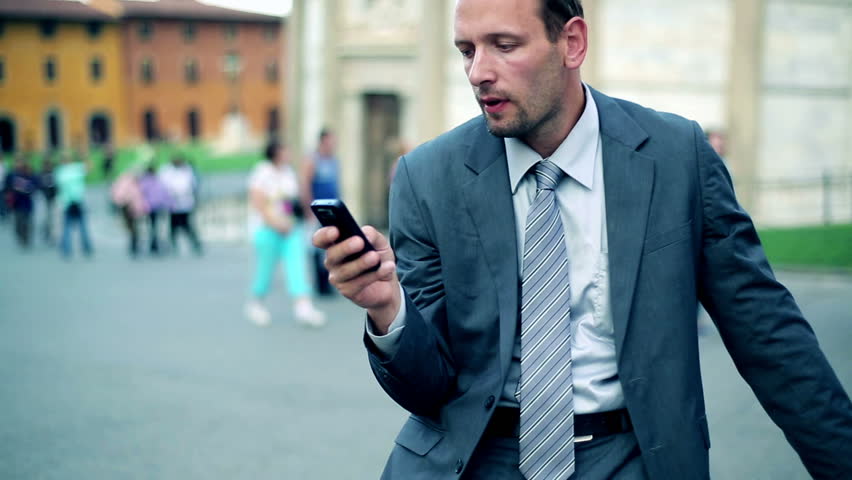 Business man in tourist city checking cell phone for new messages
