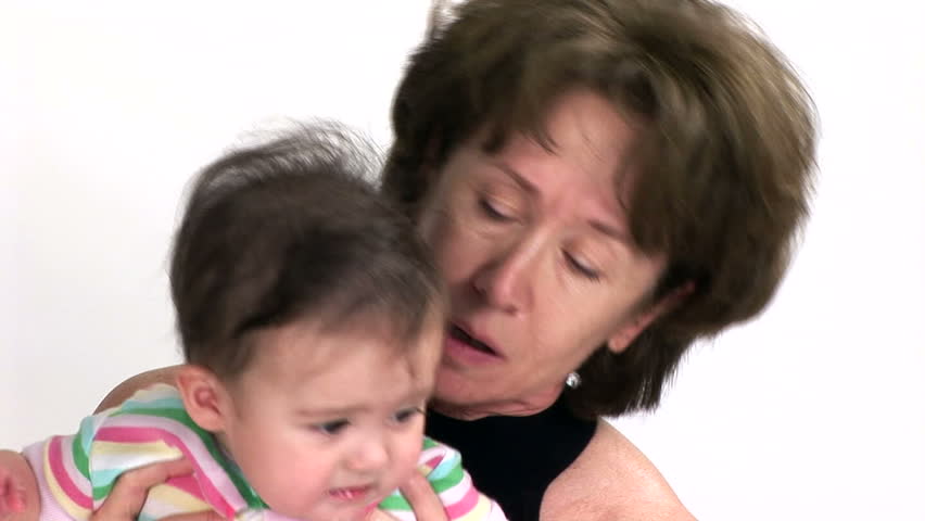 A grandmother holding her granddaughter who is becoming fussy and unhappy. 