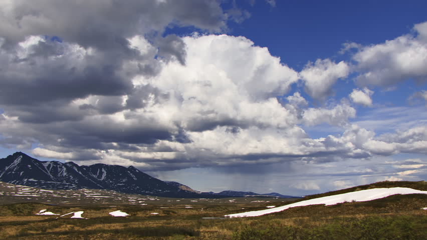 Amazing scenic vista of Alaskan tundra valley surrounded by mountains, detailed clouds moving in time lapse.
