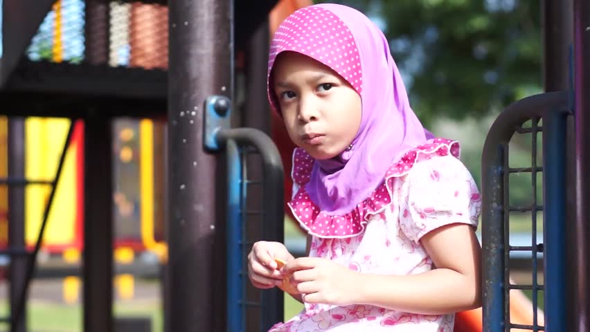 Happy muslim girl wearing scarf eat biscuits