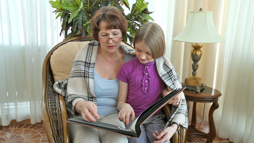 Grandma and her lovely granddaughter spending time together looking at old photographs