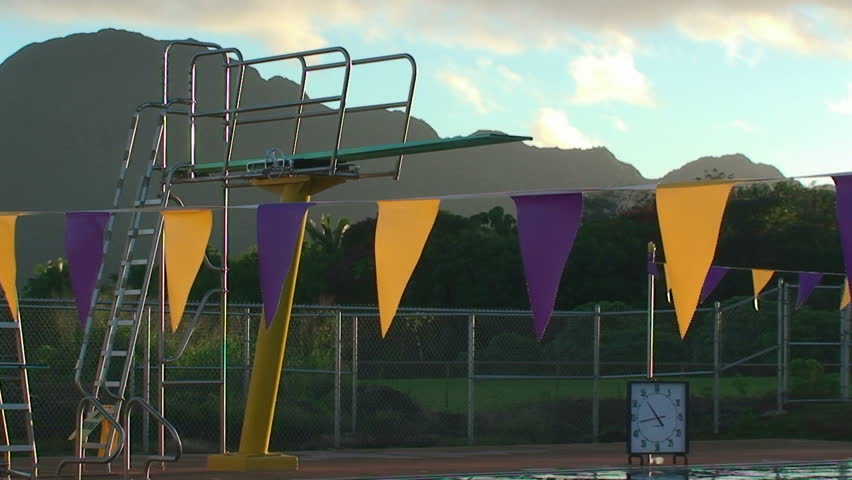 racing flags flutter in the wind with a high diving board in the background 
