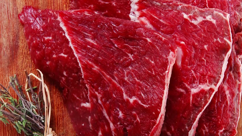 fresh raw beef meat fillet flesh with peppercorn and thyme ready to grill on wood figured old style board isolated over white background