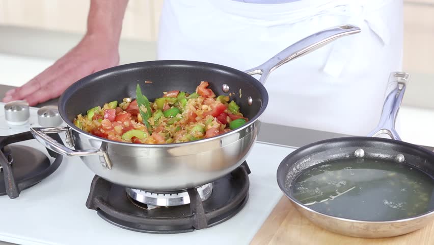 Stock being added to a rice and vegetable stew