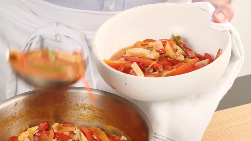 Solyanka being transferred to a soup bowl and being garnished with creme fraiche and dill