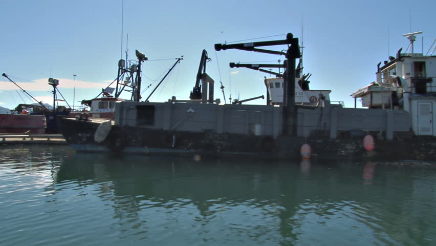 HOMER, AK - CIRCA 2012: Utility boats, cargo boats, landing craft, fishing boats, tug boats, crabbing boats. We pass them all at their moorings, side view from our boat.