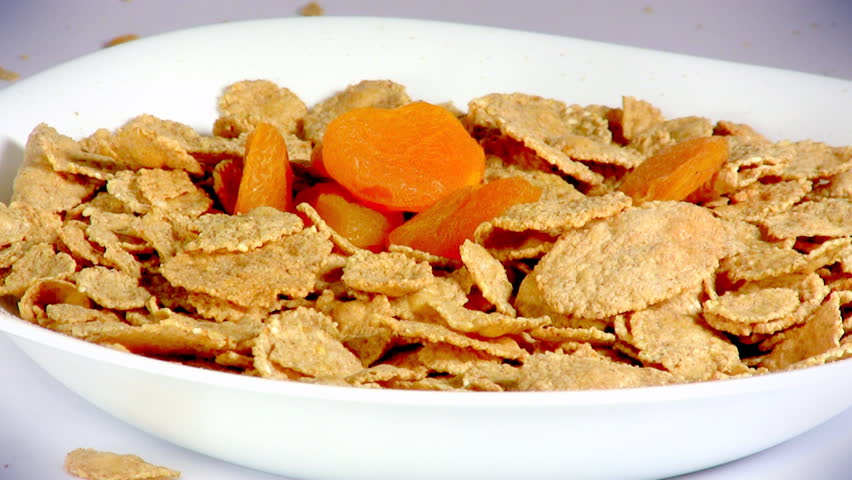 Pouring cereals, dried apricots, raisins and milk into a bowl, HD