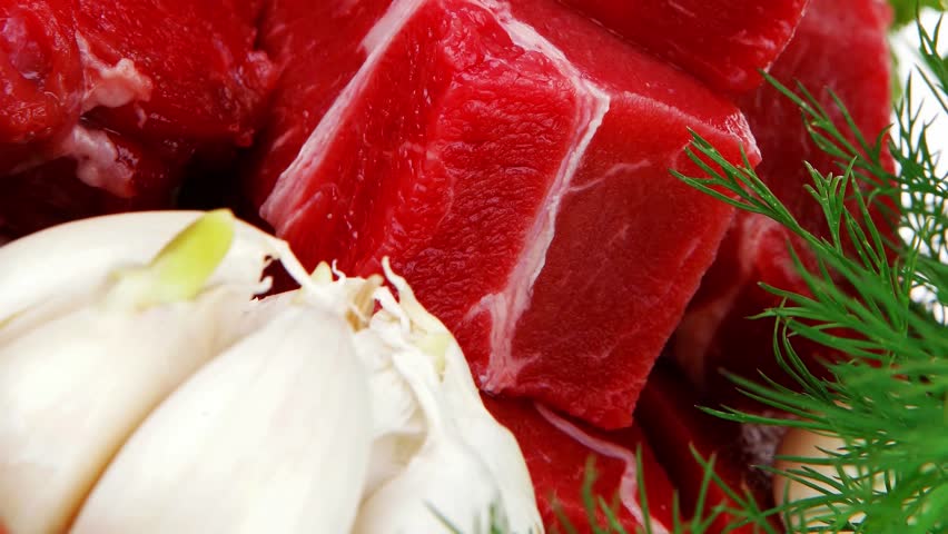 fresh uncooked beef meat slices over ceramic bowls ready to prepare with garlic and greenery isolated over white background