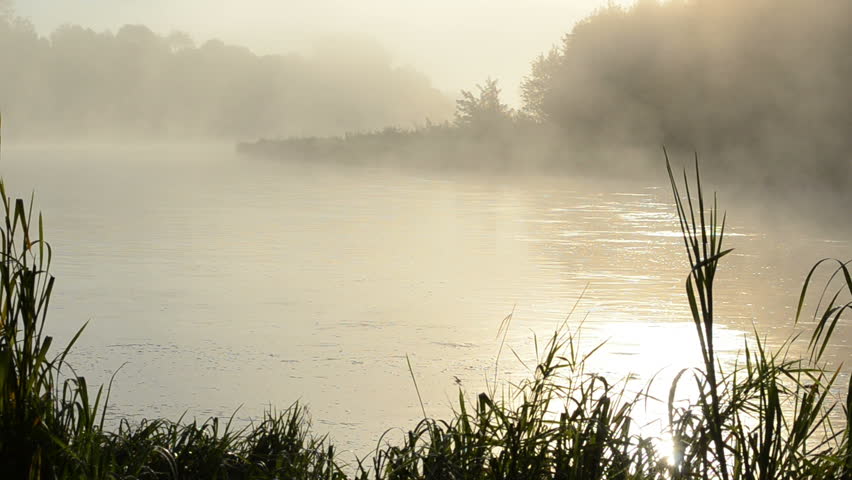 morning sunrise reflection in misty fog rise from flowing river water.
