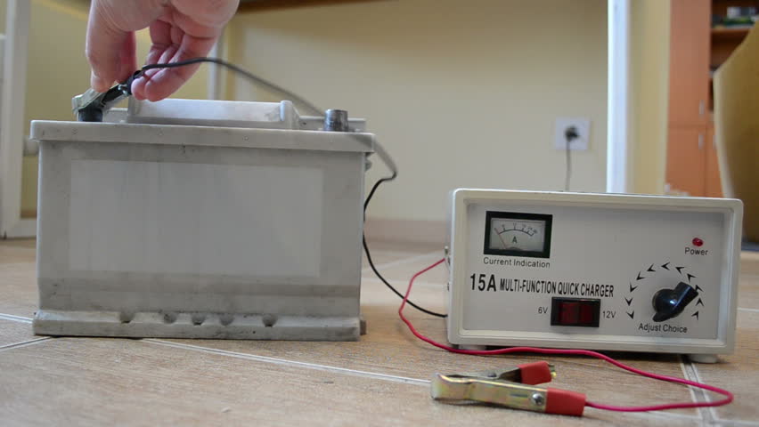 charging auto battery at home. hand put charger clamps on accumulator plus and minus.