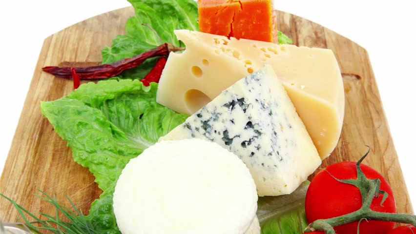 delicatessen cheeses on wooden board with vegetables olive oil and bread isolated over white background