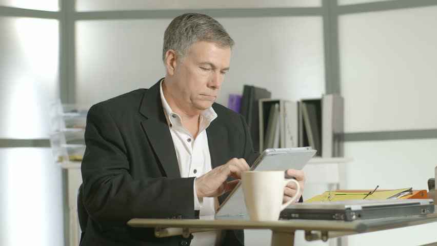 Getting up quickly from his desk a hurried businessman shows symptoms of severe back pain.