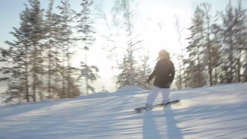 Snowboarder riding down the hill, follow shot.