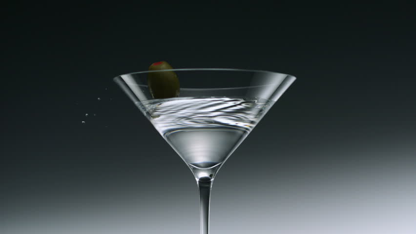 Olive falling into martini glass shooting with high speed camera.