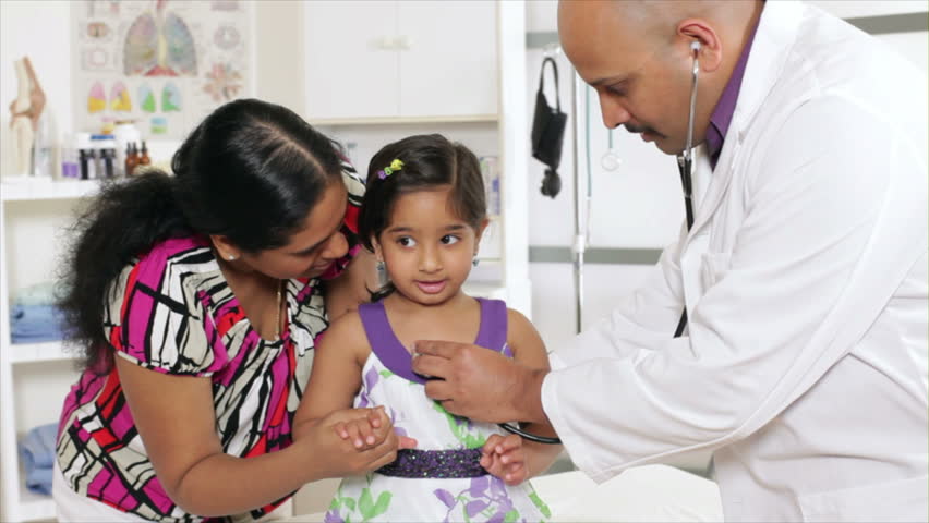 A pediatrician or family doctor gives a wellness checkup to a little patient who is being reassured by her mother.