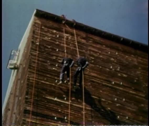 Low angle view of stunt men scaling building