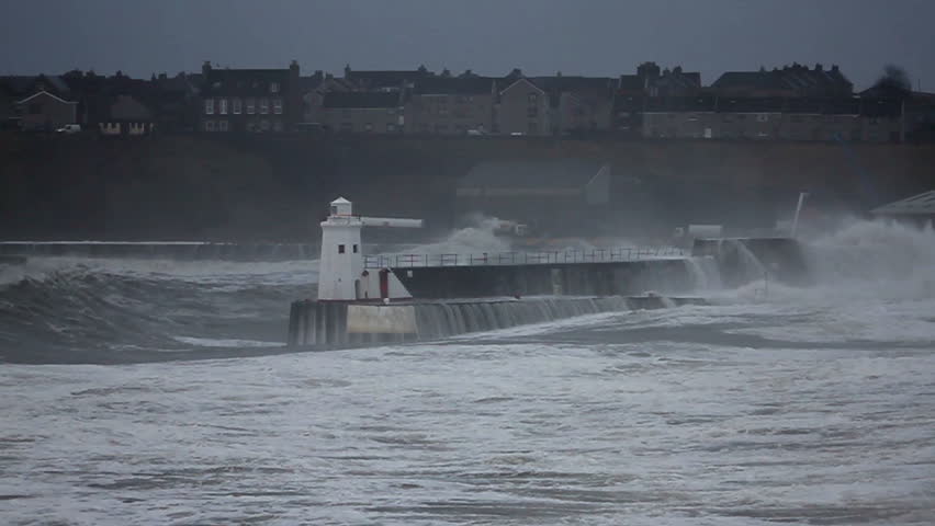 Storm waves battering harbor defenses.