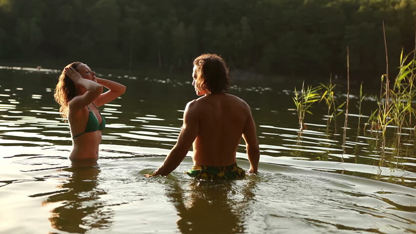 Young couple embracing and kissing in romantic attitude into the water in lonely romantic lake