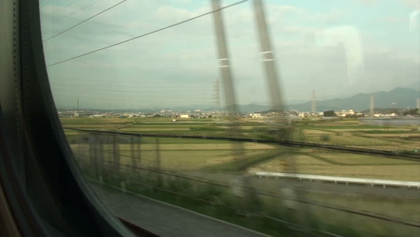 JAPAN - 16 OCTOBER 2012: A bullet train (Shinkansen) rides through rice fields as seen from inside through a window in between Tokyo and Nagoya