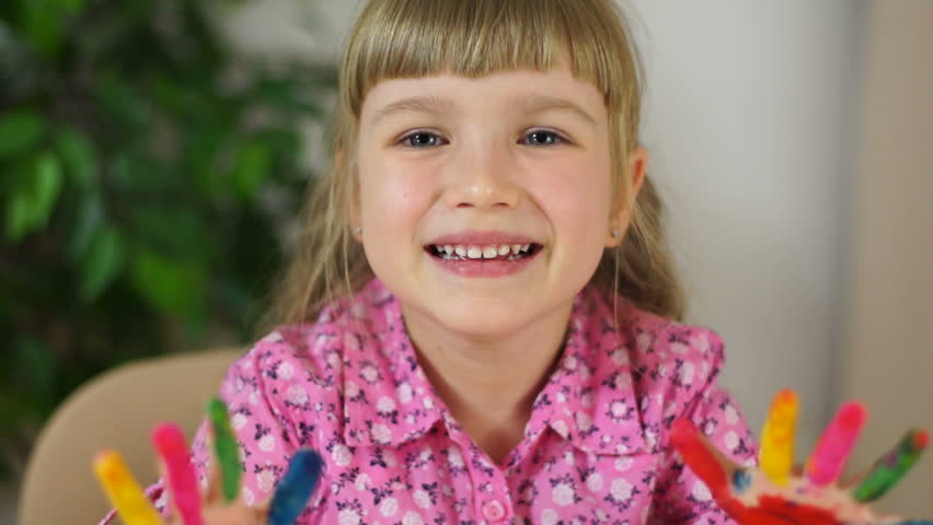 Closeup portrait funny girl coloring. Girl covered in finger paint. Selective focus. 