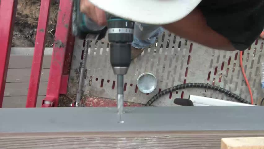 Shot from above, construction worker drills hole in wall while fighting with the torque.