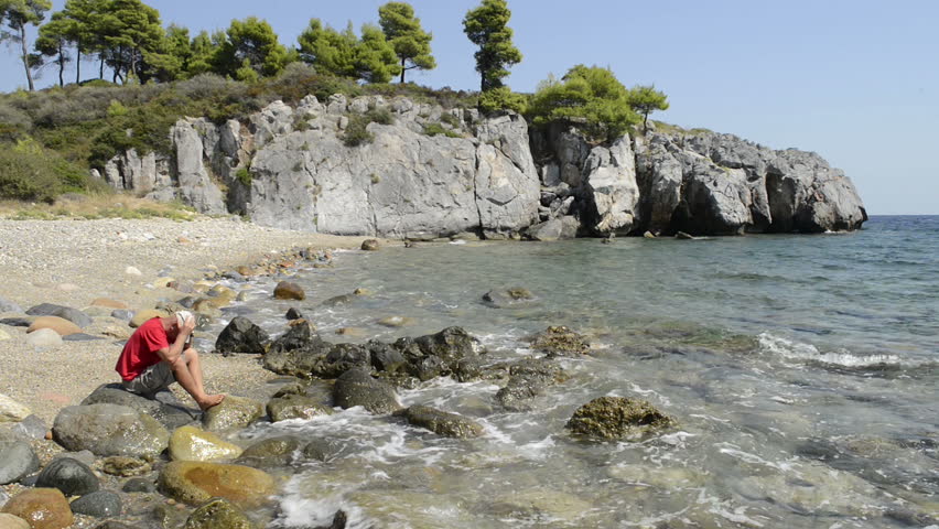 Sad looking male sat on a beach