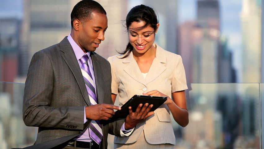 Team of confident senior managers using internet on tablet computer on rooftop in NYC