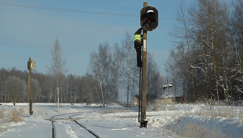 Railroad worker  with cell phone on signal beacons pole
