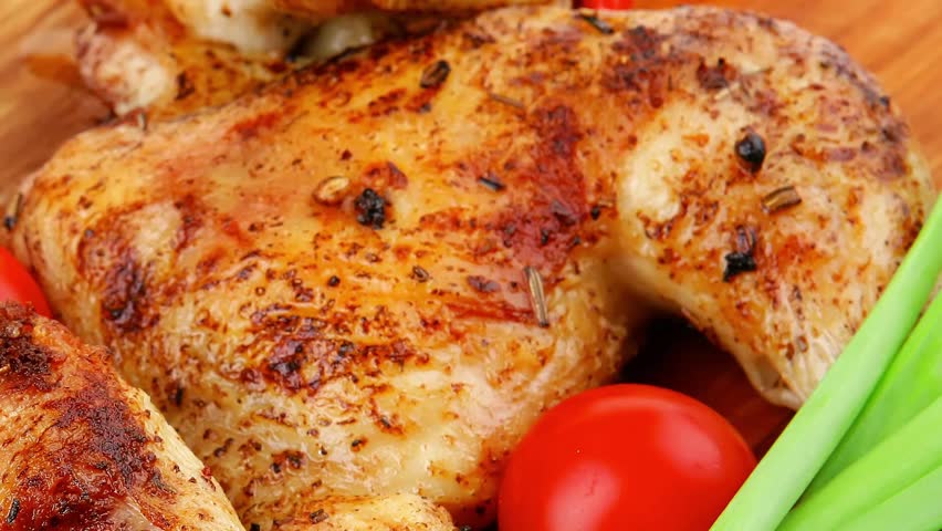 meat : grilled quarter chicken garnished with green sprouts and red peppers on wooden plate slow motion  hidef