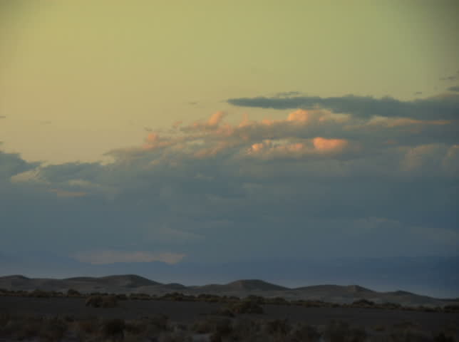 NTSC - Time lapse sunsetting clouds travel over sand dunes in Death Valley National Park, California, USA.