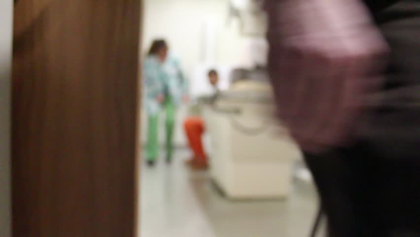 An out of focus video of a real inmate in an orange jumpsuit being xrayed.  A sheriff's deputy uncuffs him for the xray