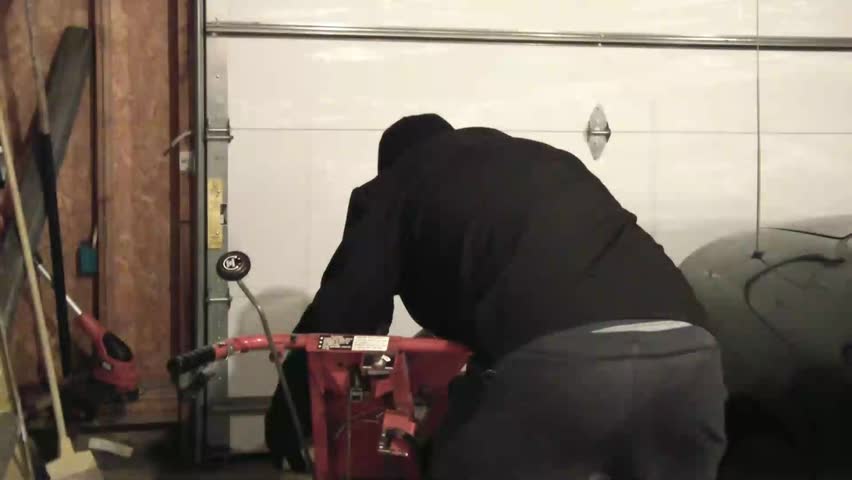 Man starts snow blower and then proceeds to leave garage to snow blow driveway at night.