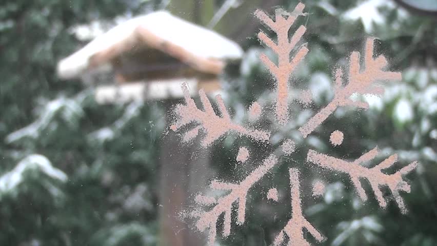 Outdoor winter garden scene with snow and a stylised snowflake decoration in the foreground for your Christmas greeting card