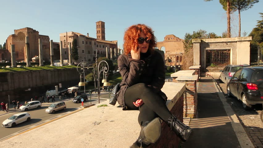Young smiling woman talking on cell phone, against colosseum