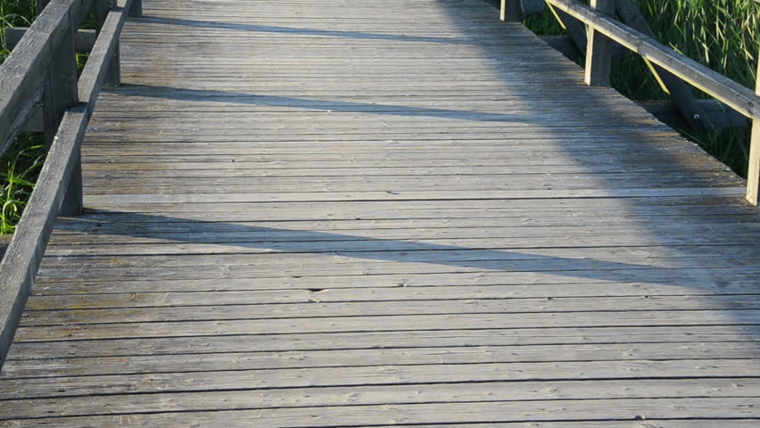 senior old man with cap drive bicycle on wooden long bridge through lake.
