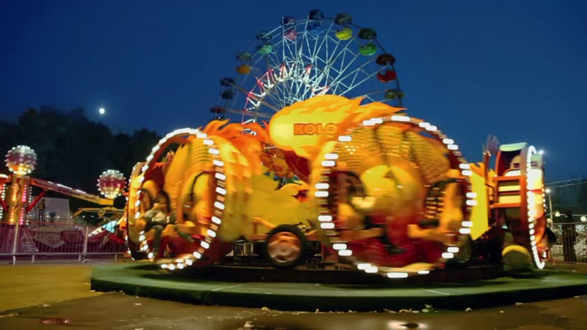 MOSCOW - OCT 8: People ride on rotary attraction Kolobok and Ferris wheel which spins with illumination at park Sokolniki, Oct 8, 2011, Moscow, Russia.