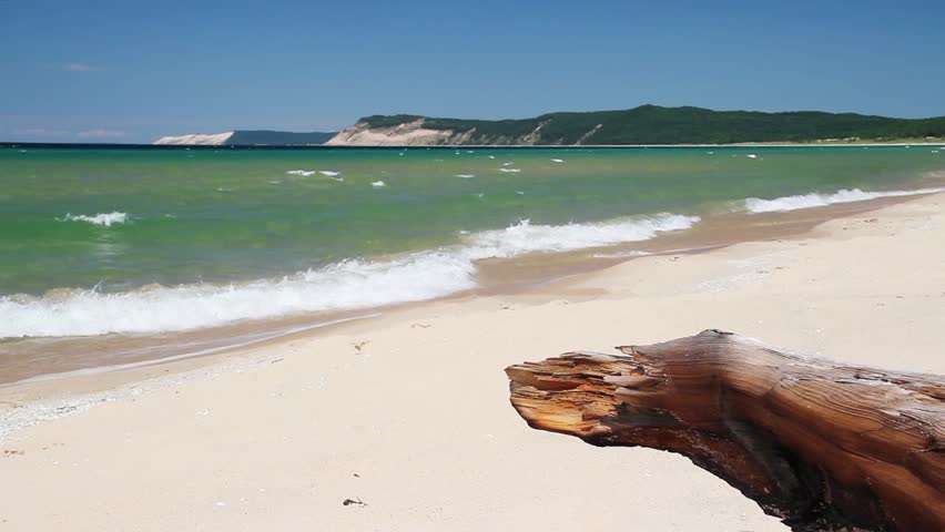 Loop features waves breaking on a Lake Michigan beach with driftwood and Sleep Bear Dune in the background. Sleeping Bear Dune National Lakeshore, Michigan.