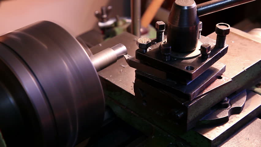 worker handles metal piece on the lathe 2