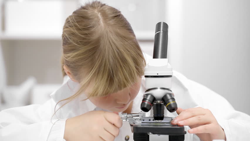 Young girl with microscope in school research lab