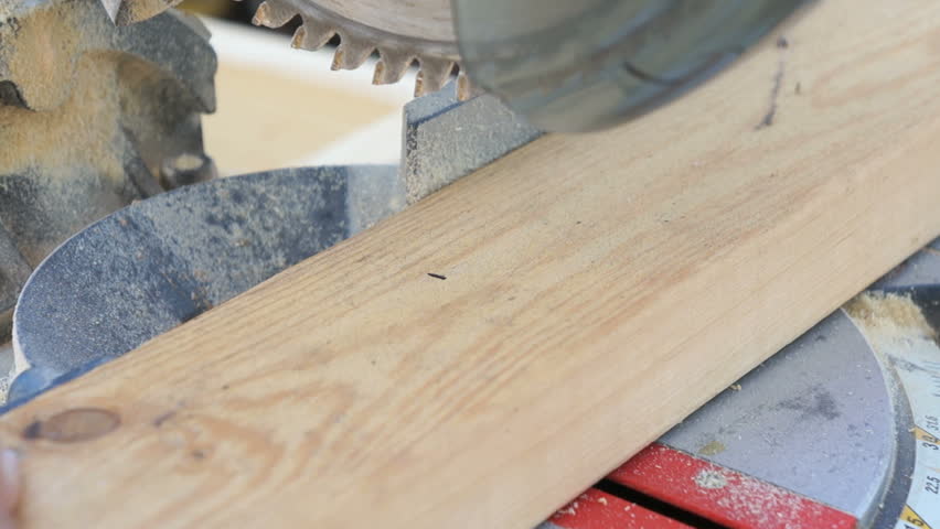 Closeup view of a miter saw cutting a 2 by 4 board at a construction site