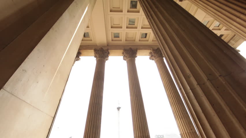 Camera tilt from pillars of National Gallery to a glimpse of Nelson's monument and finishing on the tiled floor. People are standing by the columns. 