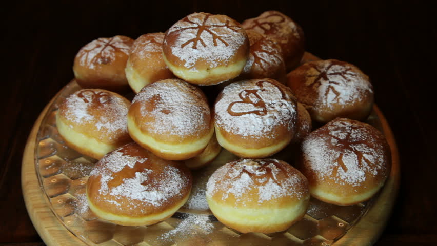 ROTATING FOOD SERIES - Sweet fresh baked donuts sprinkled with powdered sugar, slowly rotating on a glass plate,   close up- selective focus 