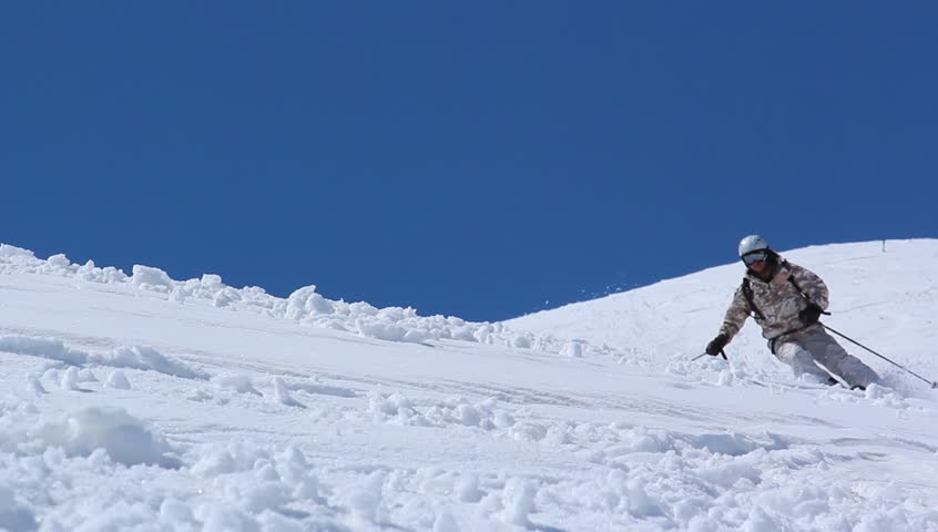 Skier close-up in soft snow on a sunny give against the clear sky