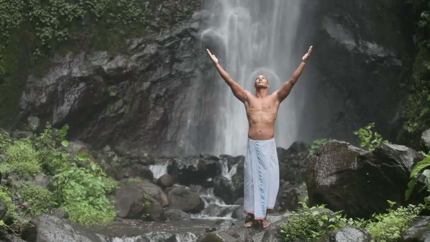 Handsome and muscular man feeling good under waterfall
